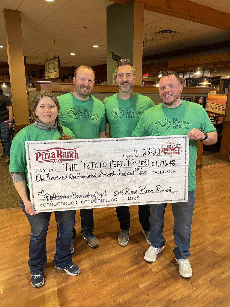 Four GBC team members hold up large check with total earnings from Pizza Ranch fundraiser